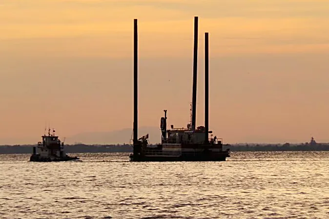 Jack-up y remolcador en mar abierto al atardecer.
