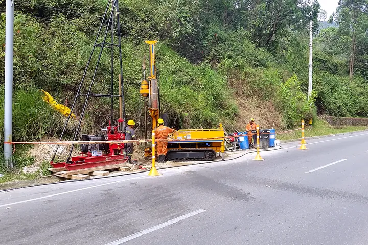 Equipo de perforación geotécnica al borde de una vía.