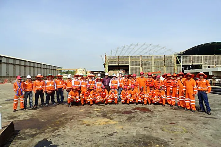Equipo de trabajo completo con overoles y cascos en un patio de obra.