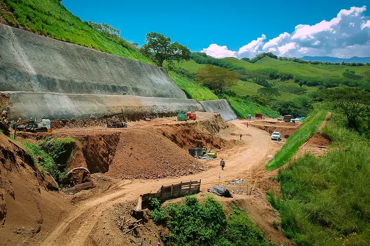 Talud estabilizado con muro de concreto bajo un cielo despejado.